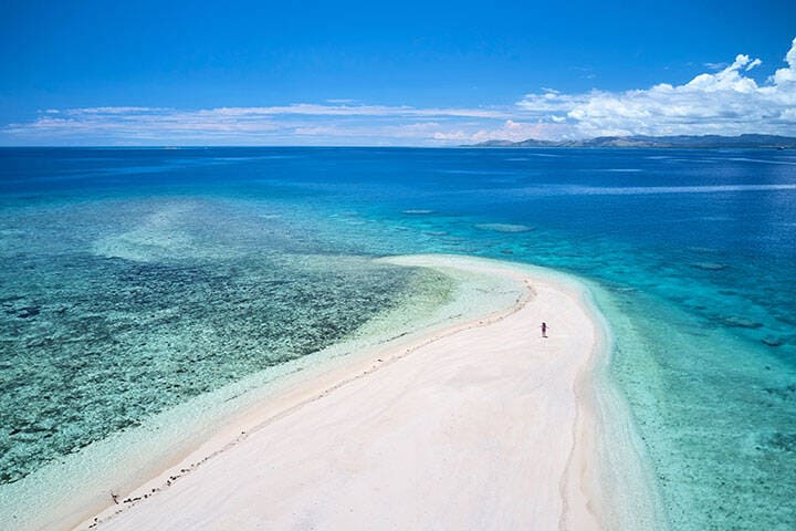 Woman on remote island in Fiji overlooking blue coral reef   