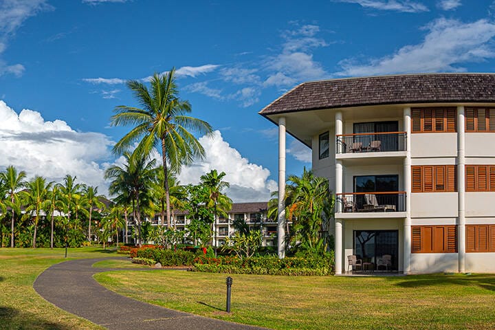Luxury Fijian resort manicured tro[ical gardens vibrant coconut palms white clouds in blue sky 
