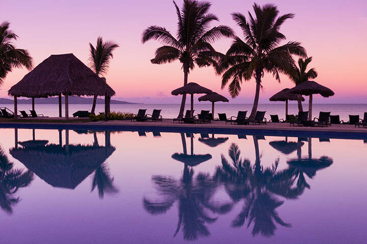 Pinkish purple sunrise colors reflecting in the water in Fiji 