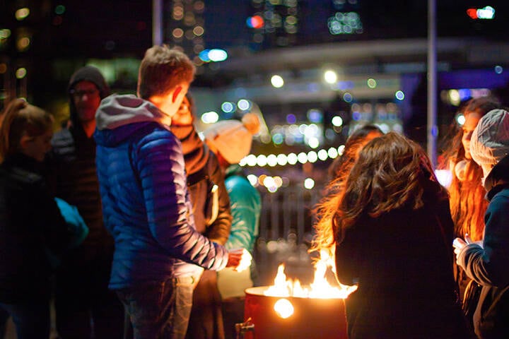 A group of young people is warming around the fire on the waterfront in Docklands in Melbourne during winter