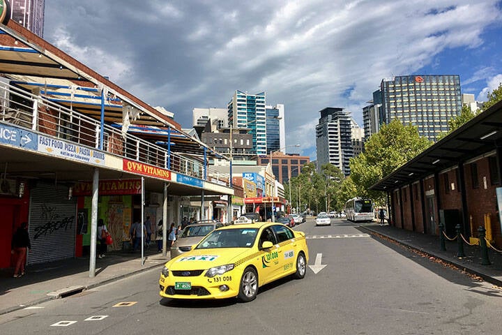A yellow taxi drives through a back street near Melbourne’s Victoria Market.