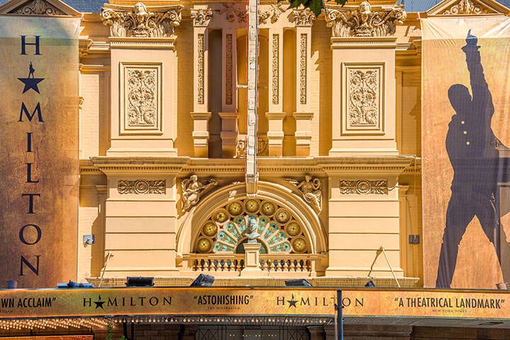 A close view of Her Majesty's Theatre in Melbourne, decorated with the signage of the musical production Hamilton