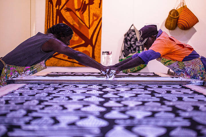 Unique Aboriginal artwork in Gunbalanya - Artists screen printing fabric at Injalak Arts and Crafts.  The Injalak Arts and Crafts Centre provides a unique opportunity to view Aboriginal artistry of very high calibre in the Aboriginal township of Gunbalanya, or Oenpelli as it is also known. There are traditional painters, bark painters, basket weavers and screen printers that travellers may also be able to see at work.
