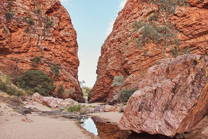 Escarpment rock at Simpsons Gap. Simpsons Gap is one of the most prominent gaps in the West MacDonnell Ranges in Australia's Northern Territory. It is located 18 kilometres west from Alice Springs, on the Larapinta Trail.  Simpsons Gap is known to the Arrernte as "Rungutjirpa. It is an important spiritual place for the Arrernte people who have inhabited the area since before European discovery.  The gap is home to various plants and wildlife, including the black-footed rock-wallaby. It is the site of a permanent waterhole
