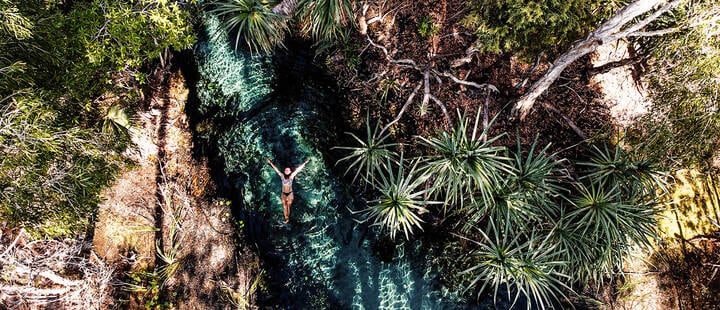 Aerial picture of a girl swimming in the hot springs in Mataranka, Australia. Beautiful clear warm river between the palm trees of Northern Territory.
