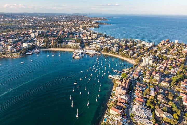 Aerial drone evening view of the Sydney suburb of Manly, a beach-side suburb of northern Sydney, in the state of New South Wales, Australia. Manly Harbour in the foreground, Manly Beach in the back. 