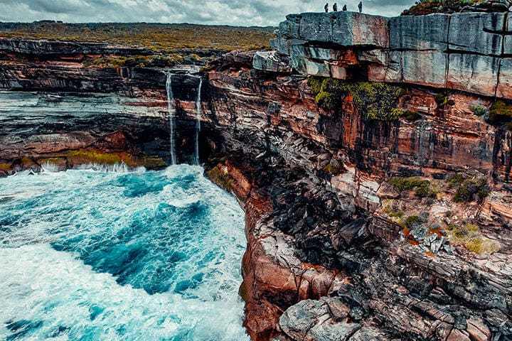 Aerial of Hikers On Top Of Eagle Rock with Curracurrong Falls In The Distance in Royal National Park, Australia