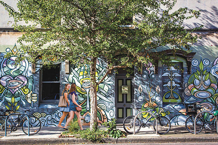 Women walking in Newtown, Sydney alongside street art 
