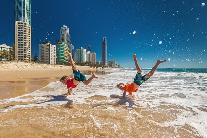Two happy boys doing hand stands on Gold Coast beach, Australia
