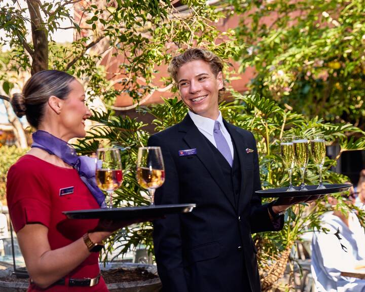 Two flight attendants serving glasses of wine at The Beresford