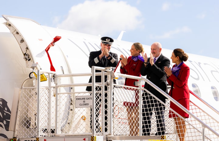 Virgin Australia cabin crew standing in Perth Airport tarmac in front of new Embraer plane