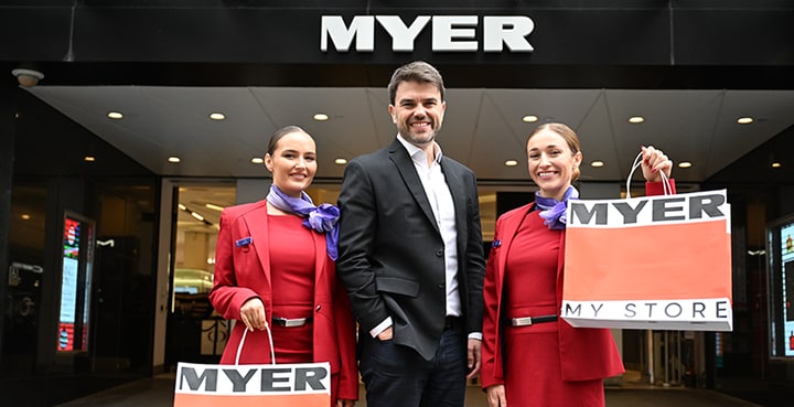 Velocity Frequent Flyer CEO standing outside of Myer shop with cabin crew holding Myer shopping bags